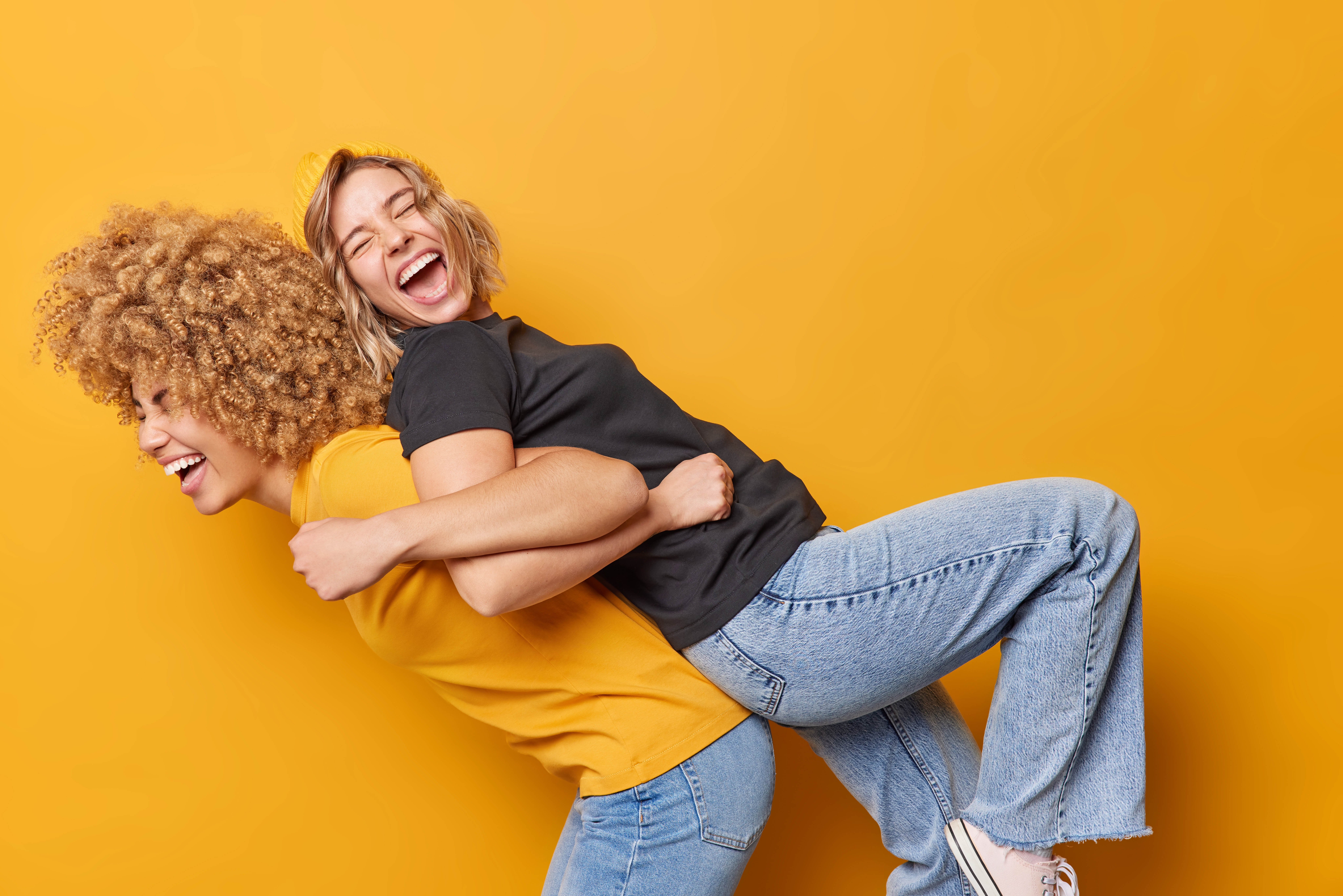 Happy women standing back-to-back and smiling and laughing